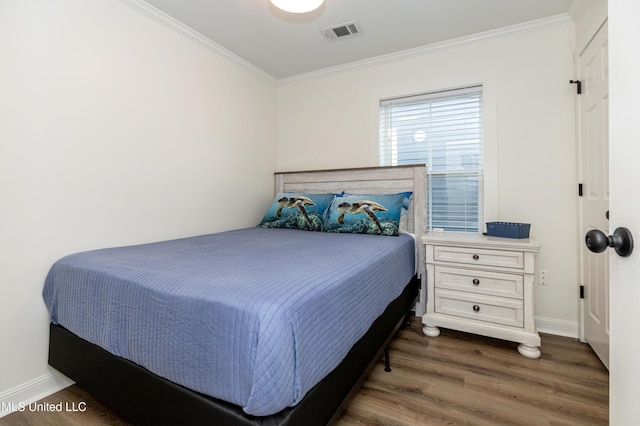 bedroom featuring baseboards, ornamental molding, visible vents, and wood finished floors