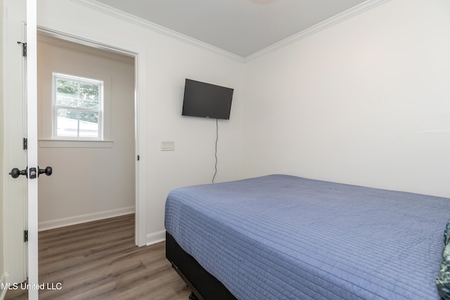 bedroom featuring ornamental molding, baseboards, and wood finished floors