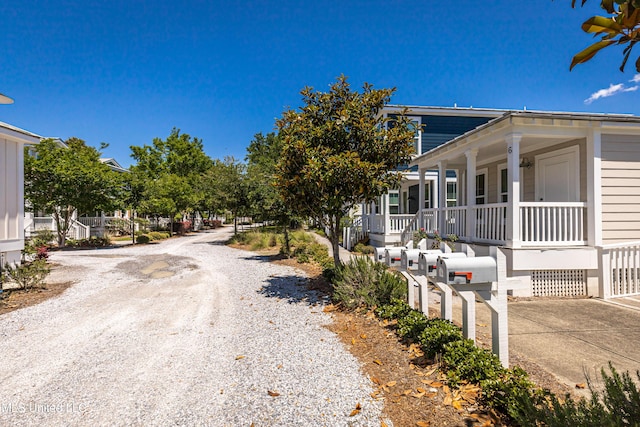view of side of home featuring covered porch and gravel driveway