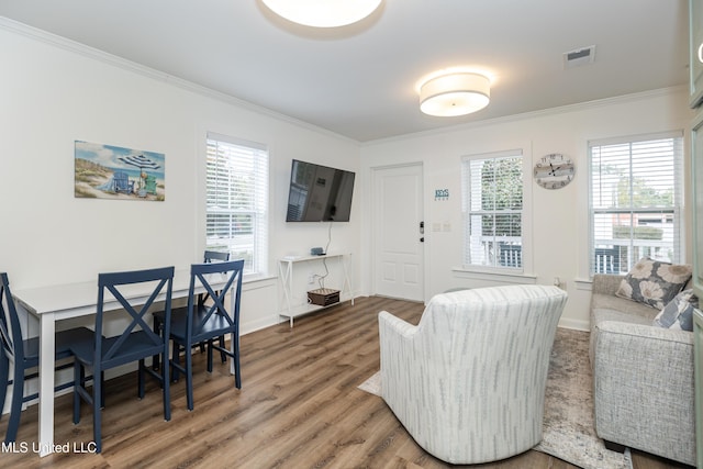 living area with ornamental molding, baseboards, visible vents, and wood finished floors