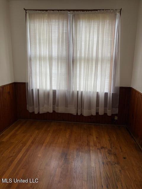 301 Hampton St, Indianola, MS 38751 - unfurnished room with wooden walls, a wainscoted wall, and wood finished floors