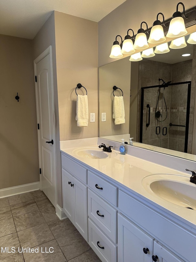 bathroom with a sink, a shower stall, baseboards, and double vanity