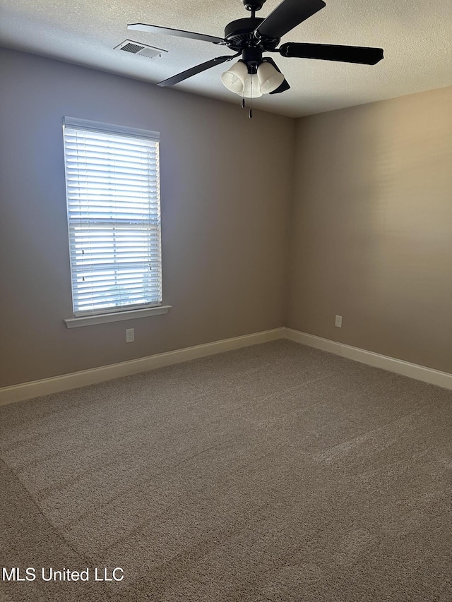 carpeted empty room featuring a ceiling fan, visible vents, a textured ceiling, and baseboards