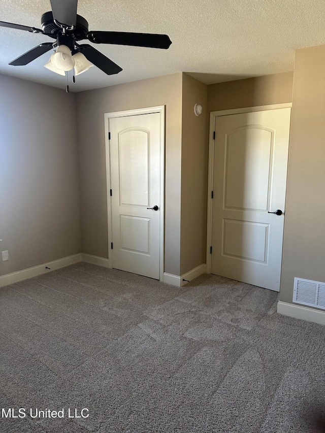 unfurnished bedroom featuring a textured ceiling, carpet, visible vents, and baseboards