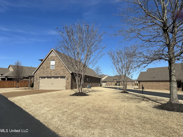 view of front of property featuring driveway, an attached garage, fence, and brick siding