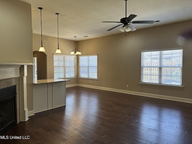 unfurnished living room featuring a textured ceiling, a fireplace, baseboards, and dark wood-type flooring