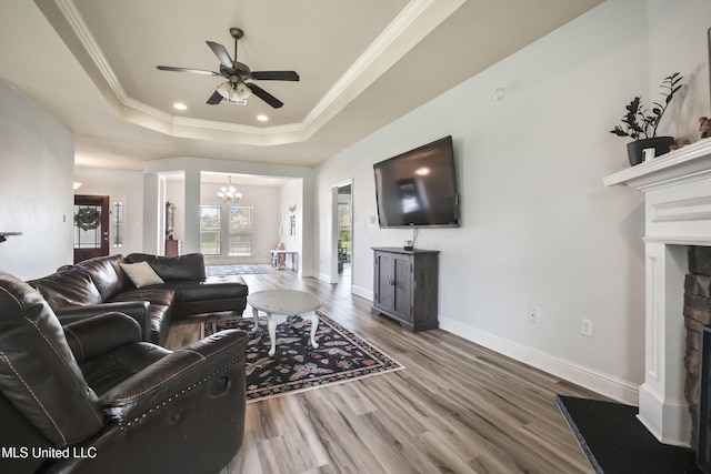 13111 Hawthorn Dr, Biloxi, MS 39532 - living room featuring a fireplace with raised hearth, a ceiling fan, a chandelier, wood finished floors, and a raised ceiling
