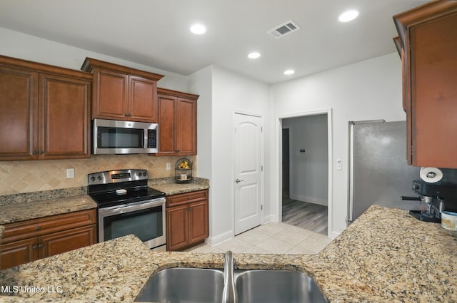 13111 Hawthorn Dr, Biloxi, MS 39532 - kitchen with appliances with stainless steel finishes, a sink, light tile patterned floors, tasteful backsplash, and light stone counters