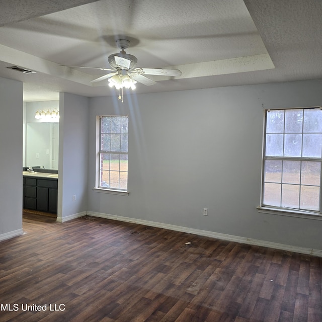 spare room with dark wood-type flooring, ceiling fan, a raised ceiling, and a textured ceiling