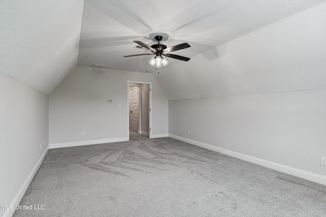 additional living space featuring lofted ceiling, a textured ceiling, carpet floors, and ceiling fan