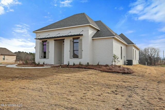 view of front of home with central air condition unit and a front yard