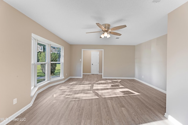 empty room featuring ceiling fan, a textured ceiling, and light wood-type flooring