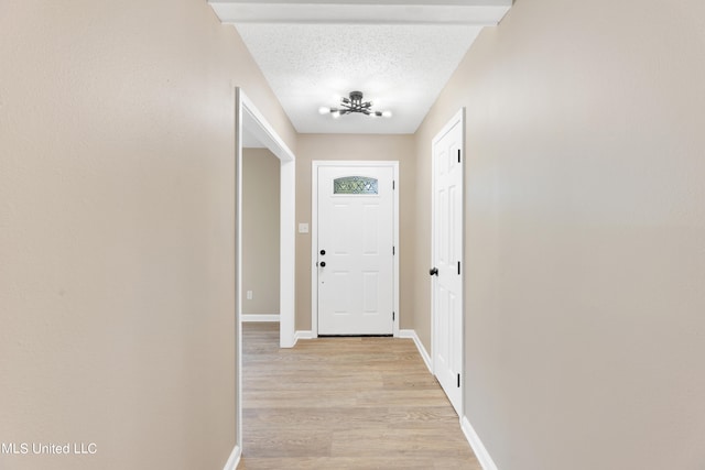 entryway with light hardwood / wood-style floors, a textured ceiling, and a chandelier