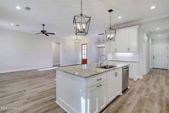 kitchen with sink, hanging light fixtures, light stone countertops, a kitchen island with sink, and white cabinets