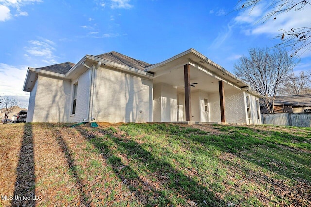 back of house with ceiling fan and a lawn