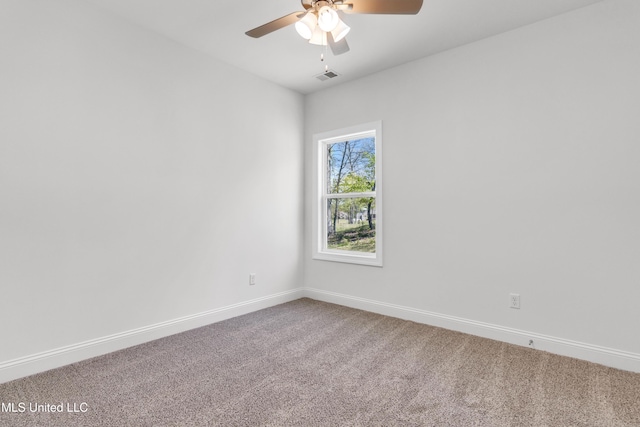 carpeted spare room featuring a ceiling fan, visible vents, and baseboards