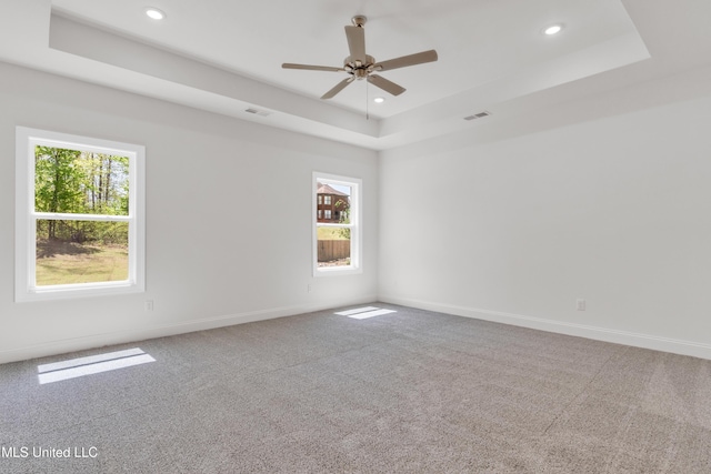 unfurnished room with carpet flooring, a raised ceiling, visible vents, recessed lighting, and a ceiling fan