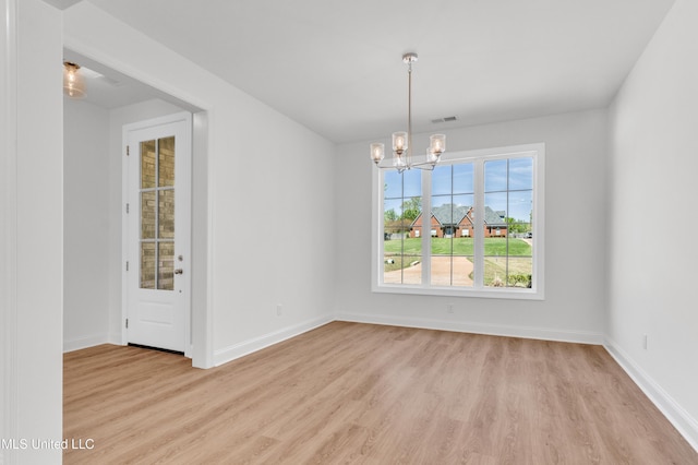 unfurnished dining area featuring visible vents, a chandelier, light wood-style flooring, and baseboards