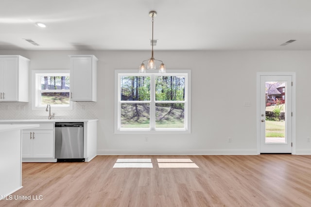 kitchen with light wood-style floors, stainless steel dishwasher, white cabinetry, and light countertops