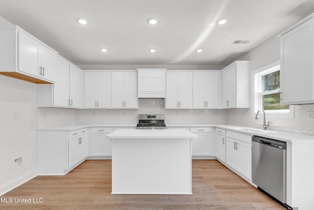 kitchen with a sink, visible vents, stainless steel appliances, light countertops, and a center island