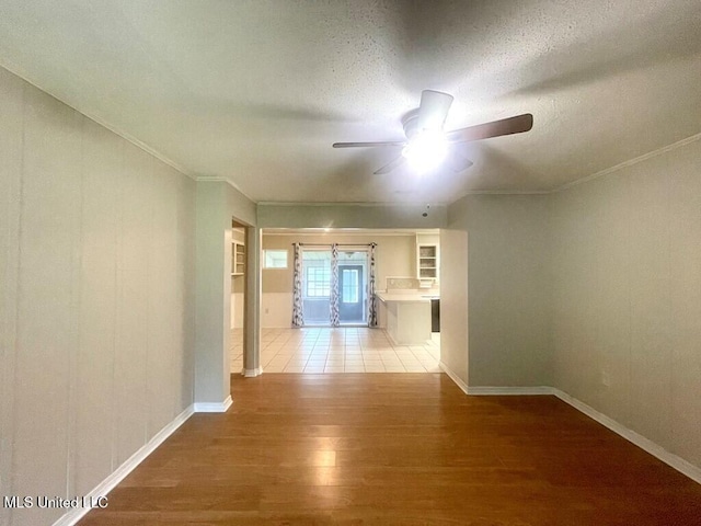 hall with ornamental molding, a textured ceiling, and light wood-type flooring