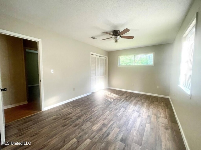 unfurnished bedroom featuring dark hardwood / wood-style flooring, ceiling fan, a closet, and a textured ceiling