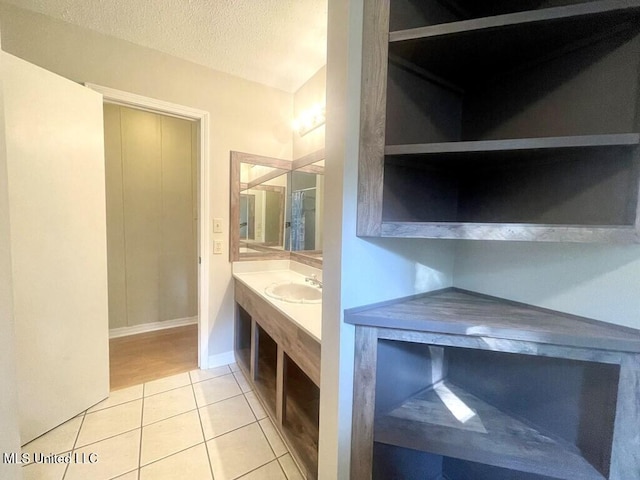 bathroom with tile patterned flooring, vanity, and a textured ceiling