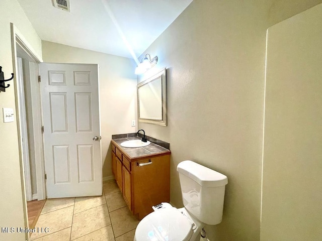 bathroom featuring tile patterned flooring, vanity, lofted ceiling, and toilet