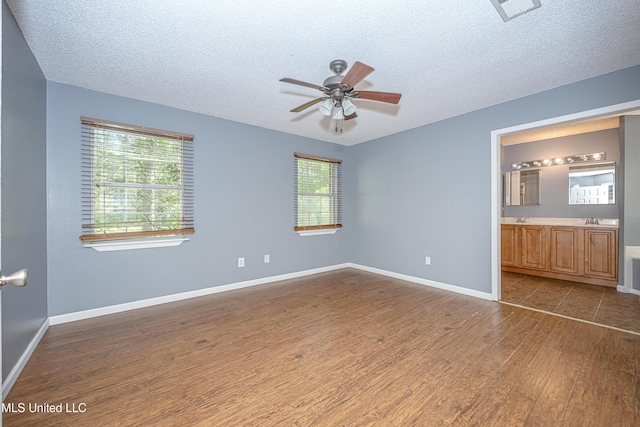 8113 Barron Rd, Moss Point, MS 39562 - unfurnished bedroom featuring dark wood-type flooring, a textured ceiling, multiple windows, baseboards, and connected bathroom