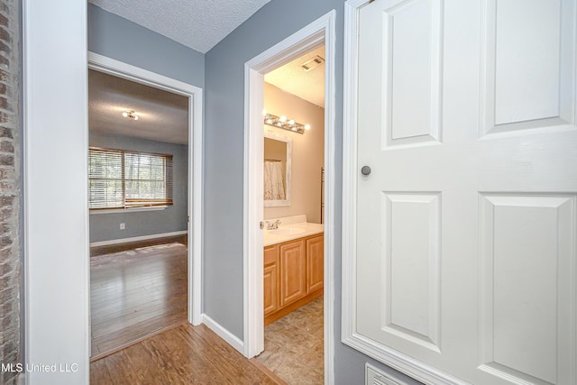 8113 Barron Rd, Moss Point, MS 39562 - bathroom with a textured ceiling, vanity, wood finished floors, and baseboards