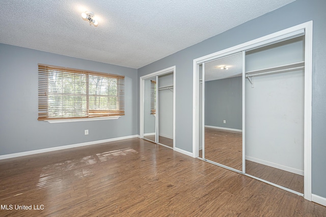 8113 Barron Rd, Moss Point, MS 39562 - unfurnished bedroom featuring multiple closets, a textured ceiling, wood finished floors, and baseboards