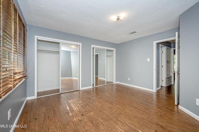 8113 Barron Rd, Moss Point, MS 39562 - unfurnished bedroom with two closets, wood finished floors, a textured ceiling, and baseboards