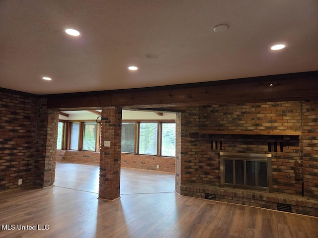 329 Arapaho Ln, Madison, MS 39110 - unfurnished living room featuring brick wall, wood finished floors, healthy amount of natural light, a fireplace, and recessed lighting