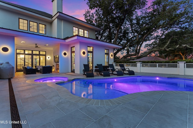 pool at dusk featuring a patio area, ceiling fan, an in ground hot tub, and an outdoor living space