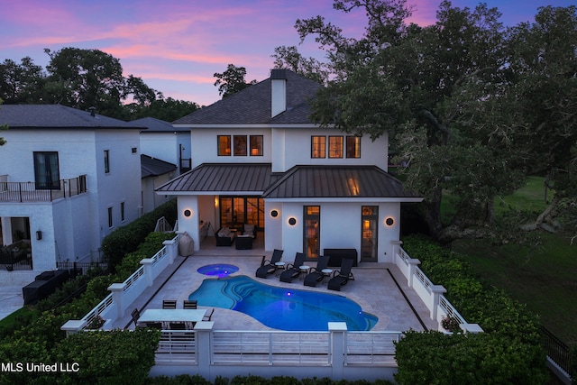 back house at dusk featuring a patio area, a fenced in pool, a balcony, and outdoor lounge area