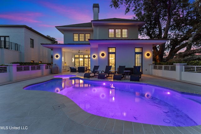 pool at dusk featuring a patio and ceiling fan