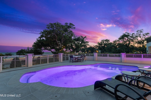 pool at dusk featuring a patio area