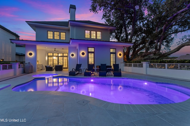 pool at dusk featuring a patio, ceiling fan, and outdoor lounge area