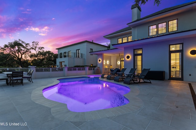 pool at dusk featuring a patio area