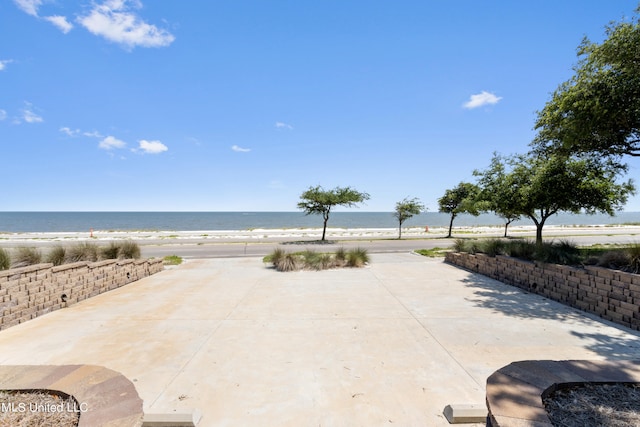 view of patio with a water view and a beach view