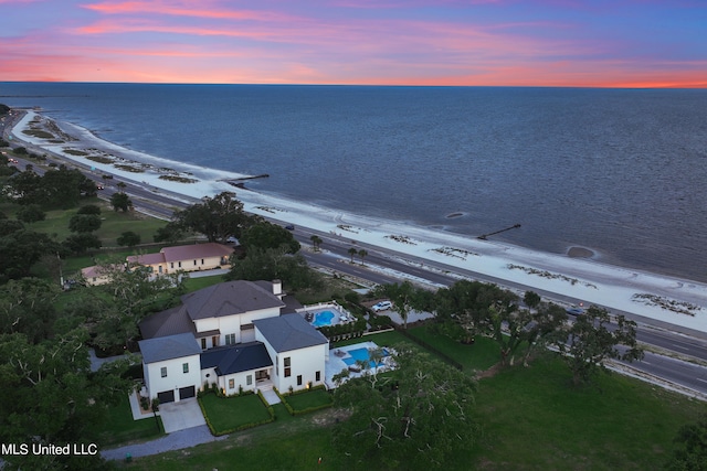 aerial view at dusk with a view of the beach and a water view