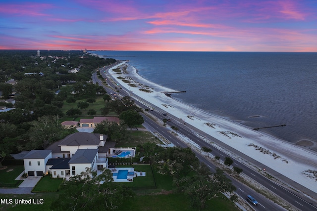 aerial view at dusk with a water view and a view of the beach