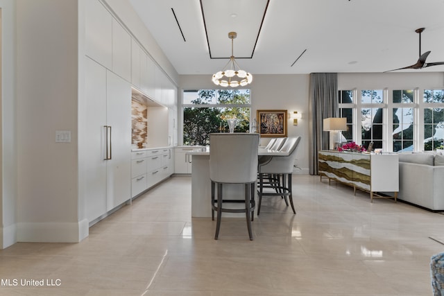 kitchen with white cabinets, a healthy amount of sunlight, a chandelier, and hanging light fixtures