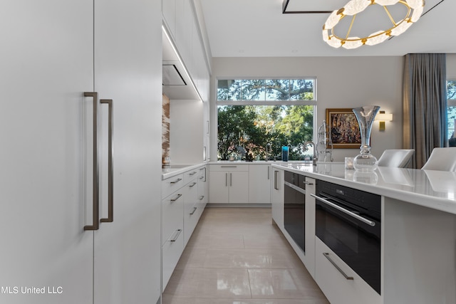 kitchen featuring fridge, hanging light fixtures, white cabinets, light tile patterned floors, and a chandelier