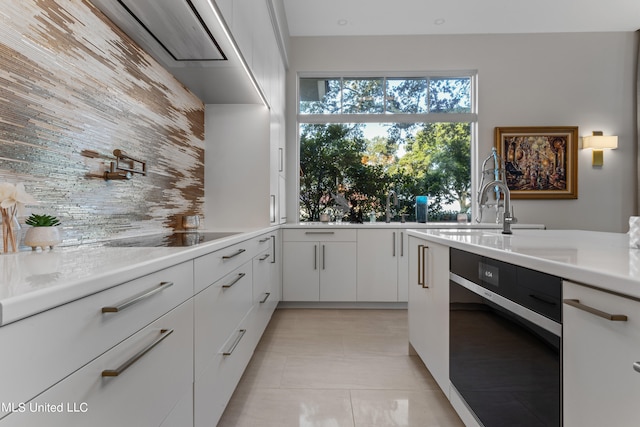 kitchen with black electric stovetop, white cabinets, dishwasher, and light tile patterned floors