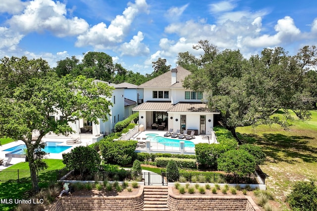 rear view of property featuring a patio area and a fenced in pool