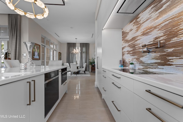 kitchen featuring a notable chandelier, white cabinetry, light stone countertops, and decorative light fixtures