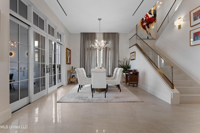 dining room with a towering ceiling, an inviting chandelier, and french doors