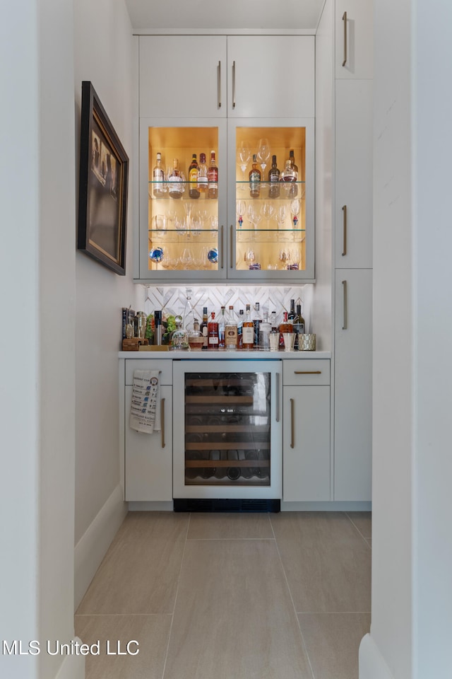 bar featuring wine cooler, white cabinets, backsplash, and light tile patterned floors