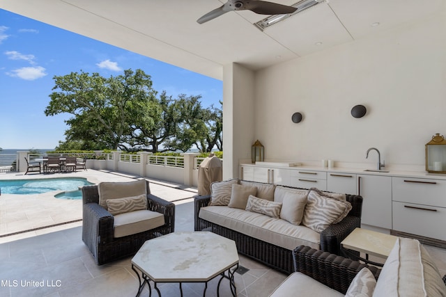 view of patio with ceiling fan, a fenced in pool, and sink